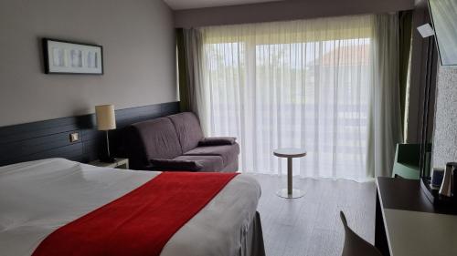 um quarto de hotel com uma cama e um sofá em Kyriad Angoulême Nord Champniers- Hôtel & Résidence em Champniers