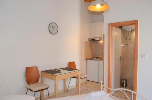 Habitación con mesa, sillas y reloj en la pared en Apartman Romana en Trogir