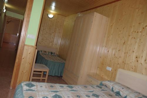 1 dormitorio con paredes de madera, 1 cama y 1 silla en CASA RURAL JAVIER EL BALCÓN APARTAMENTO 6 PERSONAS, en Las Majadas