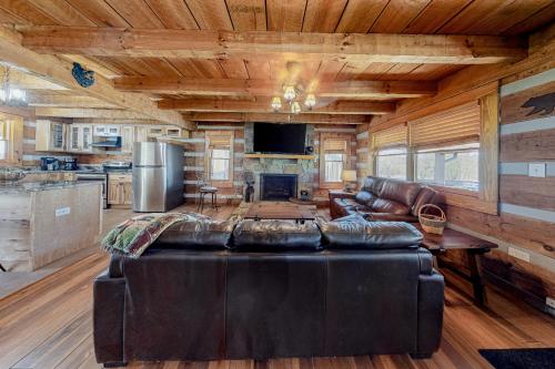 a living room with a leather couch and a kitchen at Friendly Bear Two in Sevierville