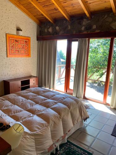sypialnia z dużym łóżkiem i dużymi oknami w obiekcie Cabaña julian w mieście La Cumbrecita