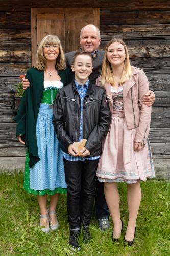 a family posing for a picture in front of a cabin at Pension Fürhapter mit Bio- Bauernhof in Sankt Jakob in Defereggen