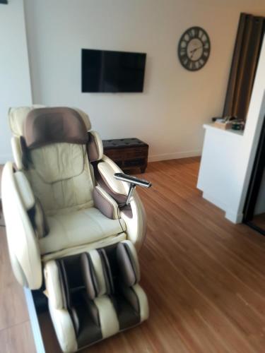a reclining chair in a living room with a clock at Suite room jacuzzi sauna privatif illimité Clisson in Clisson