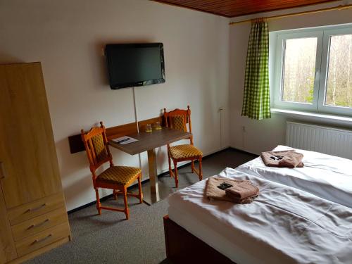 a bedroom with two beds and a table and a television at Hotel Sasanka in Tatranská Lomnica