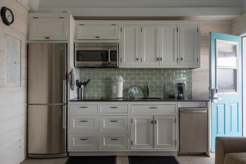 a kitchen with white cabinets and a refrigerator at Driftwood Resort on the Ocean in Montauk