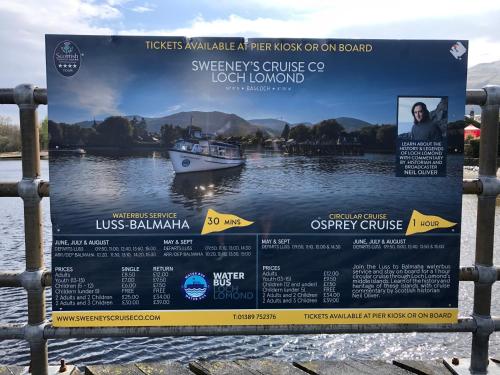 a sign on a fence with a boat on the water at Levenview Holiday Apartment Loch Lom in Balloch