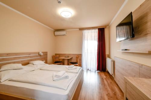 a bedroom with two beds and a tv and a table at Hotel R&oacute;zsa Cs&aacute;rda in Hegyeshalom
