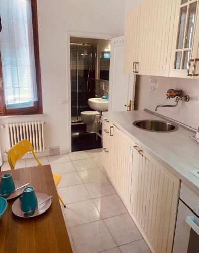 a kitchen with white cabinets and a sink and a table at casetta di Vernazza in Vernazza