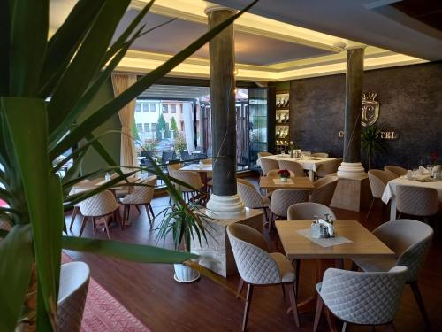 ein Restaurant mit Tischen, Stühlen und Pflanzen in der Unterkunft Conti Hotel & Restaurant in Gjakove