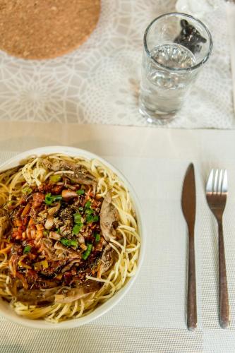 a plate of spaghetti on a table with a glass of water at Sat Nam Village Hotel in Sigiriya