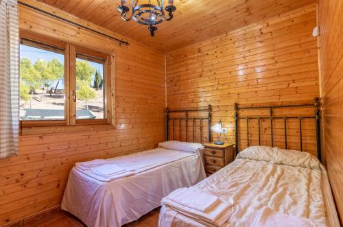 two beds in a log cabin with a window at ALEDORURAL in Aledo