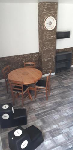 a wooden table and chairs with a clock on a wall at À 18min du ZOO 30min des 24h du Mans in Le Lude