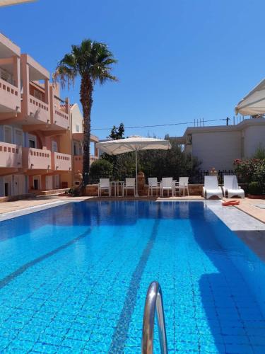 a large swimming pool with chairs and a palm tree at Toulipa Rooms in Agia Ermioni