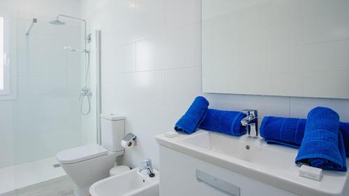 biała łazienka z niebieskimi ręcznikami na zlewie w obiekcie Blancazul Villa Verode w mieście Playa Blanca