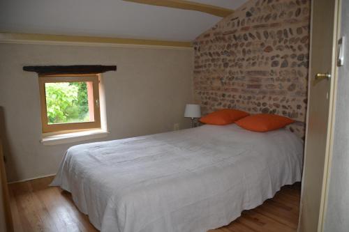 une chambre avec un lit blanc et un mur de briques dans l'établissement CHANT DU BUC, le Galet, à Marssac-sur-Tarn