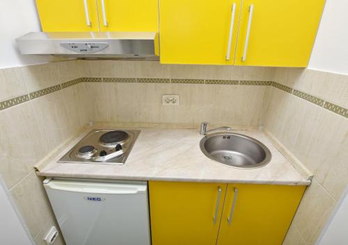 a small kitchen with a sink and yellow cabinets at Apartments and Rooms Iva in Petrovac na Moru