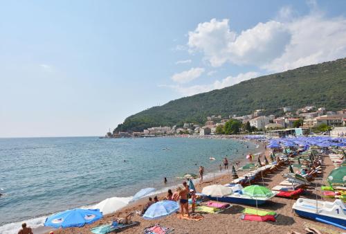 a group of people on a beach with umbrellas at Apartments and Rooms Iva in Petrovac na Moru