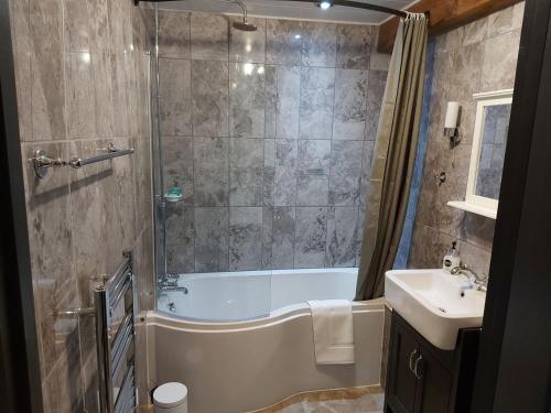 a bathroom with a shower and a tub and a sink at Greenvale Barn in Cheadle