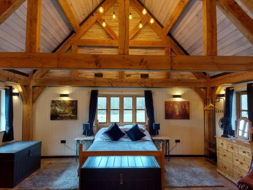 um quarto com uma cama num quarto com tectos em madeira em Greenvale Barn em Cheadle