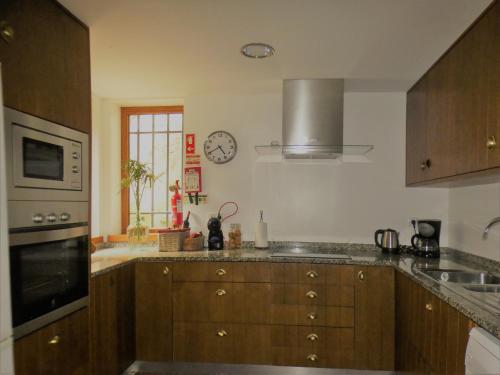 a kitchen with wooden cabinets and a clock on the wall at Rio d'Azenha - Country House in Roliça