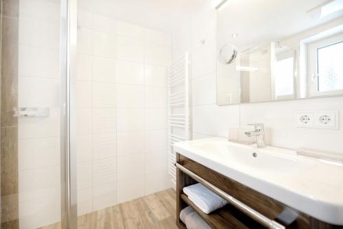 a white bathroom with a sink and a shower at Hotel Alpina Superior in Pettneu am Arlberg