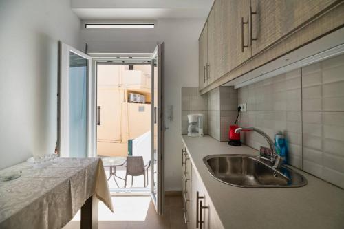 une cuisine avec un évier en acier inoxydable et une table dans l'établissement Irini-Kalamaki-apartments, à Kalamaki