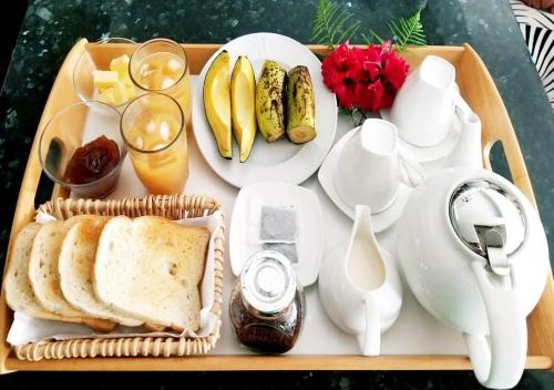 a tray of food with bread and fruit and drinks at La Nature Apartments Au Cap in Mahe