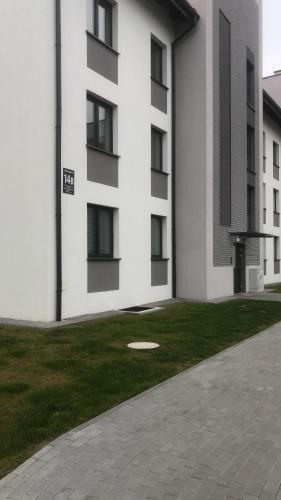 a white building with a grass yard next to a building at Apartament Gościnne Sady in Malbork