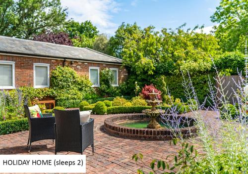 a garden with a patio with a fountain and a house at Cadnam Lodge in Cadnam