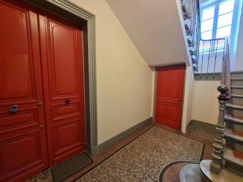 a hallway with red doors and a staircase with a window at Appartement intra muros 8 personnes climatisé Wifi stationnement facile in Avignon