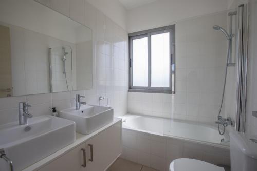 ein Badezimmer mit zwei Waschbecken, einer Badewanne und einem WC in der Unterkunft Esprit Villa 30 in Polis Chrysochous