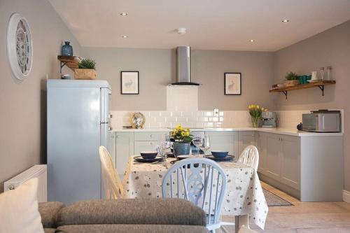 a kitchen with a table with chairs and a refrigerator at Kilbroney River Cottage in Rostrevor