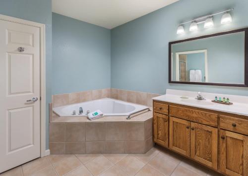 a bathroom with a tub and a sink and a mirror at Club Wyndham Governors Green in Williamsburg