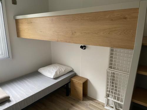 uma pequena cama num pequeno quarto com uma janela em Mobilhome tout confort R10 domaine de lanniron em Quimper