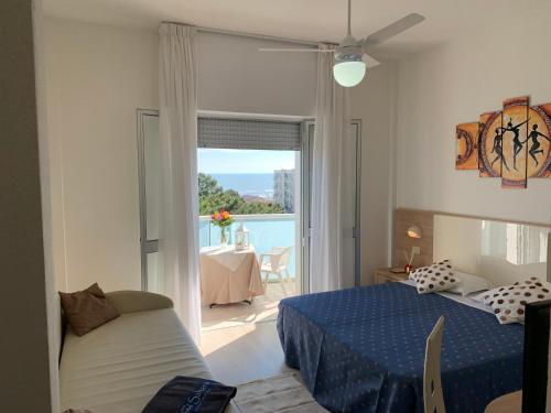 a bedroom with a bed and a couch and a window at Hotel Sahara in Milano Marittima
