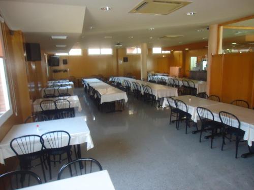 un comedor con mesas y sillas blancas en Hotel Restaurant Casa Miquel, en Alcarraz