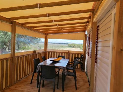 une terrasse couverte avec une table et des chaises. dans l'établissement Superbe Mobil home "excellence" au MAR ESTANG, à Canet