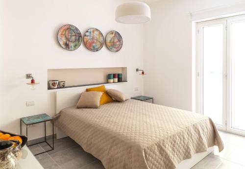 een witte slaapkamer met een bed en twee borden aan de muur bij Damè - Accommodation Amalfi Coast in Maiori