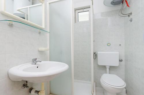 a white bathroom with a sink and a toilet at Apartments Massimo in Rovinj