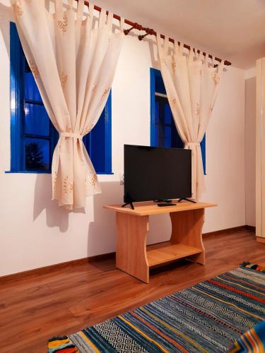 a living room with a tv and two windows at Casa Pavel Jurilovca in Jurilovca