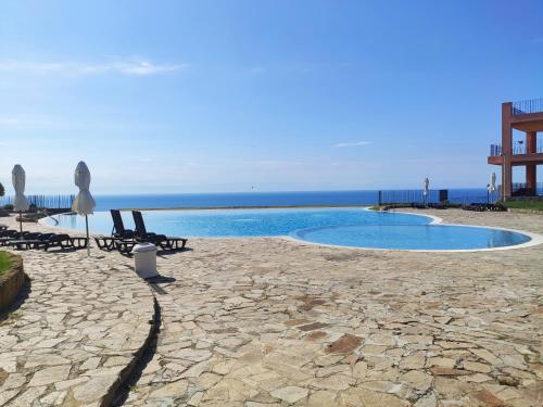 einen Pool mit Stühlen und das Meer im Hintergrund in der Unterkunft Nana apartment in Kaliakria resort in Topola