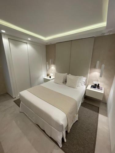 1 dormitorio con 1 cama blanca grande y 2 mesas en Amarella Suite, en Marbella