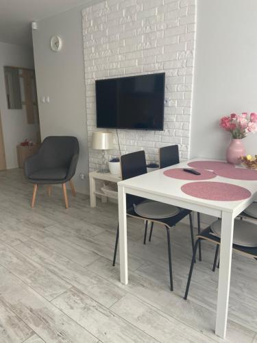 ein Wohnzimmer mit einem Tisch und Stühlen sowie einem TV in der Unterkunft Apartament Słoneczny II in Dziwnówek
