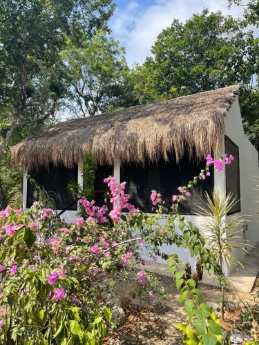 a cottage with a thatched roof and flowers at Maya Eco Village in Akumal
