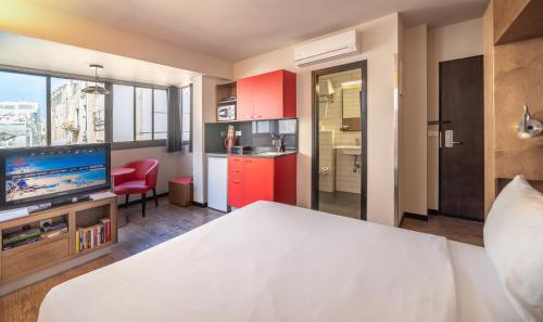 a bedroom with a bed and a tv and a kitchen at Ben Yehuda Apartments in Tel Aviv