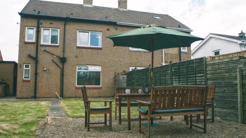 a table and two chairs with an umbrella at Dwellcome Home Ltd 3 DOUBLE Bedroom House Boldon, Ideal for long term contractor, etc stays, Free Parking, Fast WIFI, 3 miles 7 mins drive to Nissan, 15 mins to Sunderland Newcastle, Regular Housekeeping Options - see our site for assurance in Boldon