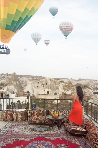 a woman sitting on a balcony looking at hot air balloons at Kismet Cave Mansion in Göreme