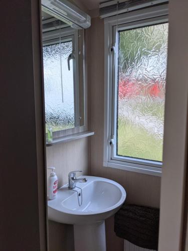 La salle de bains est pourvue d'un lavabo et d'une fenêtre. dans l'établissement 17 Sun Valley Holiday Park, à St Austell