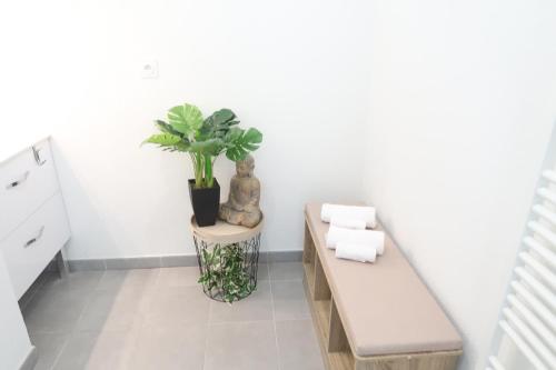une chambre blanche avec un banc et une plante en pot dans l'établissement Logement Entier - Appartement T2 Confort - Toulouse - Balcon Aménagé, à Toulouse