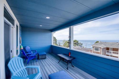 a blue porch with chairs and a large window at The Captains Lookout Sleeps 6, Hot Tub, Pet Friendly, Ocean View in Depoe Bay